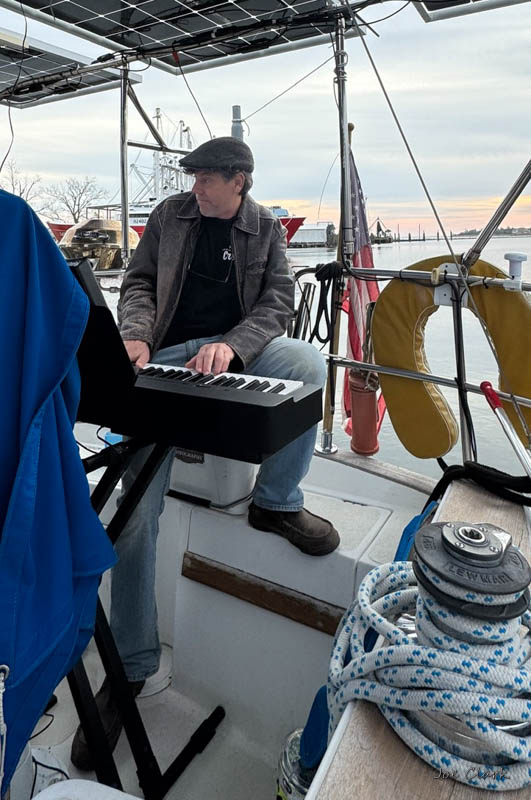 Christopher Siren playing piano aboard a sailboat in Oriental, NC.
